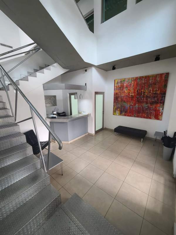 Reception area with desk, metal staircase, abstract art, tile floors in commercial building Panama