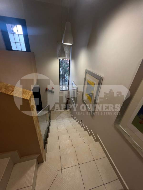 Wide staircase with glass railing, tile floors, pendant lights and artwork in Residencial Versalles Panama