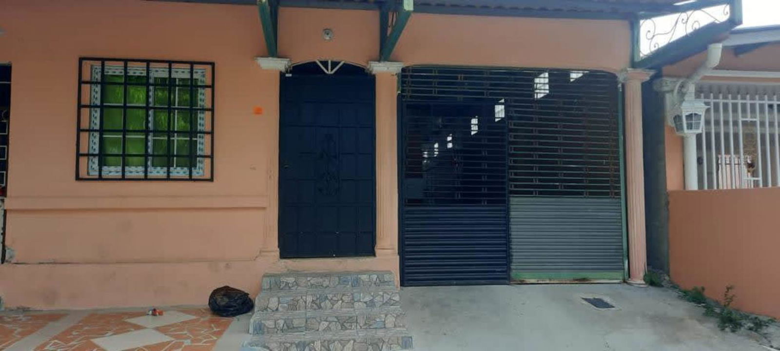 Covered garage entrance with metal security gate in affordable Nuevo Tocumen house Panama