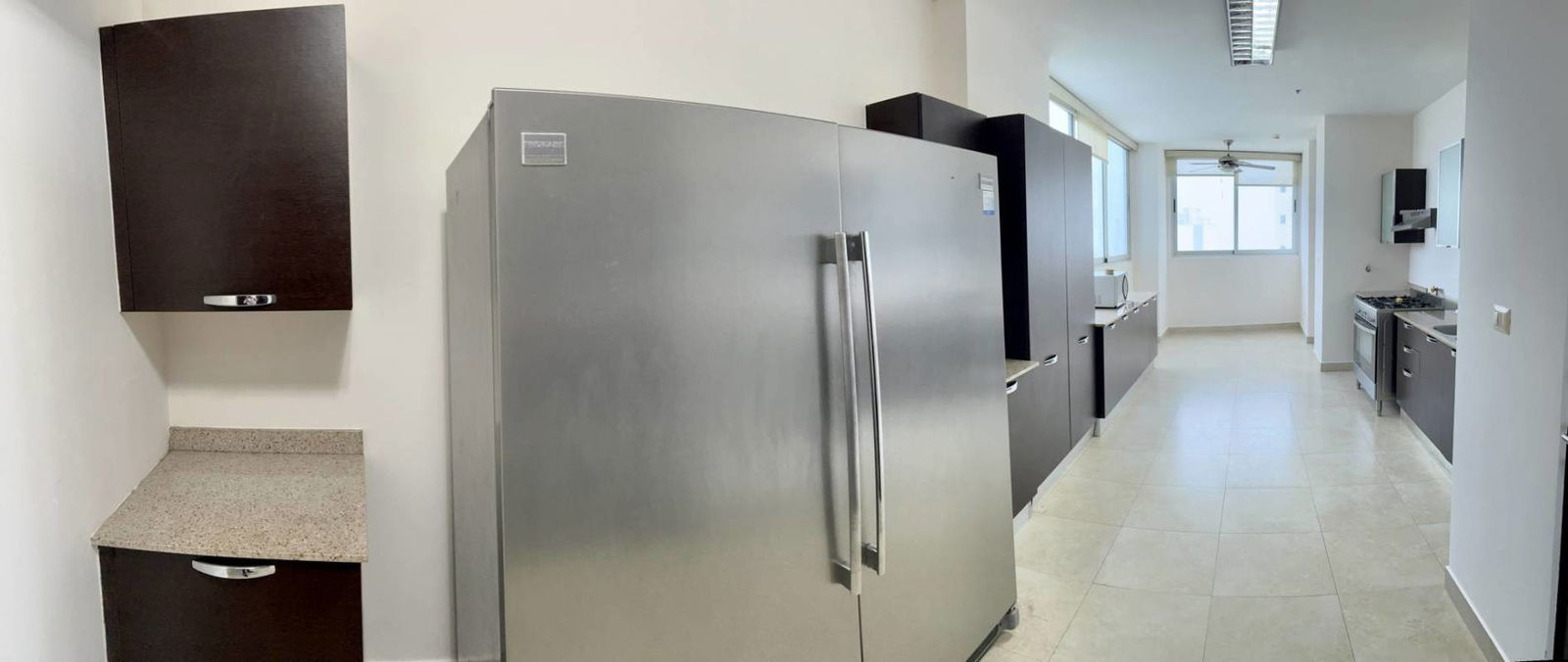 Sleek kitchen with stainless steel refrigerator, gas stove, microwave, granite countertops, and balcony access at PH Pearl at the Sea in Panama