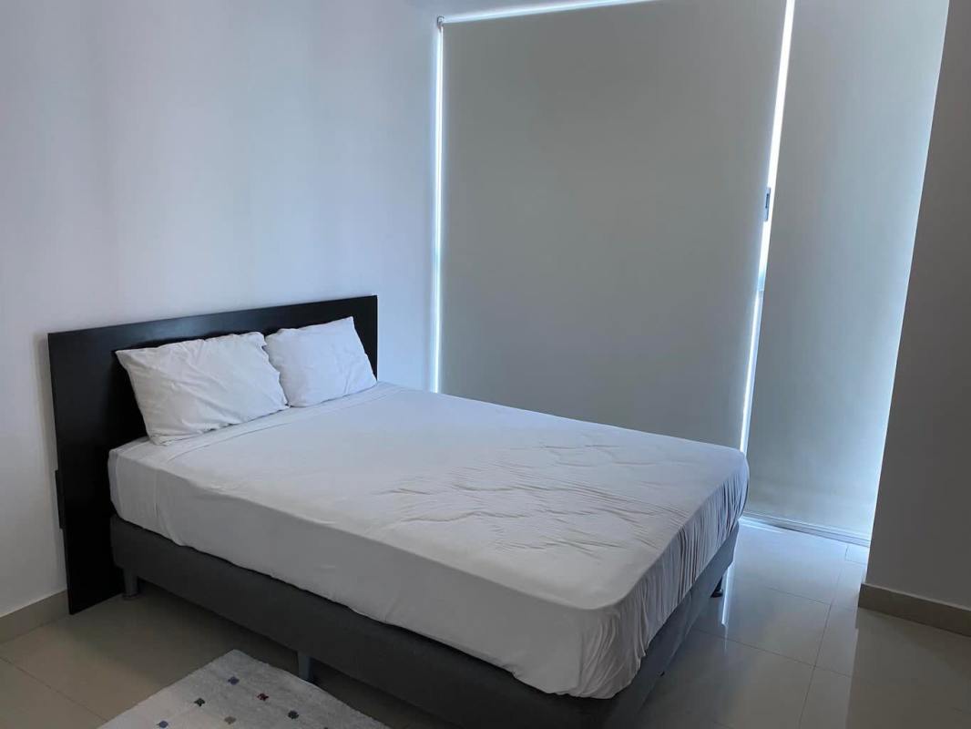 Bedroom with floor-to-ceiling windows showing ocean and skyline, porcelain floor, neutral decor PH Waterfalls