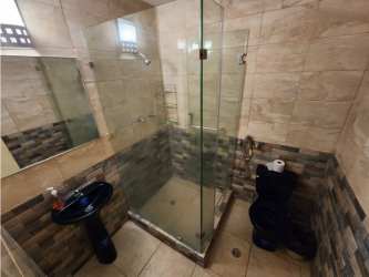 Modern bathroom with glass enclosure, tiled walls in Los Balcones Playa Blanca Panama