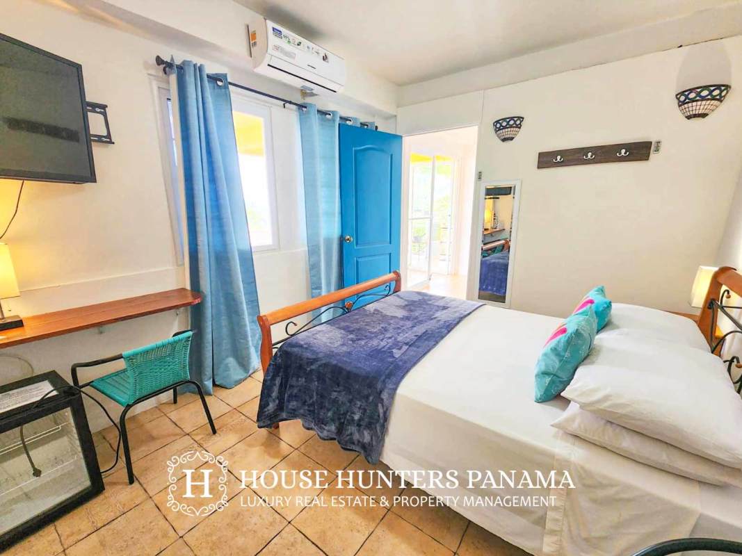 Bright guest room with AC, wooden bed, tile flooring, tropical décor at boutique hotel Isla Taboga Panama