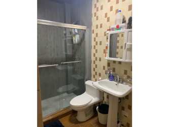 Modern bathroom with glass shower enclosure, pedestal sink, tile walls in Altos de María mountain house