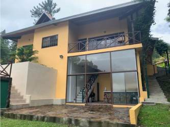 Two-level yellow house with balcony, large windows, surrounded by lush gardens in Altos de María Panama