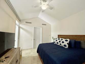 Modern bedroom with vaulted ceiling, king bed, flat screen TV in beachfront loft Buenaventura