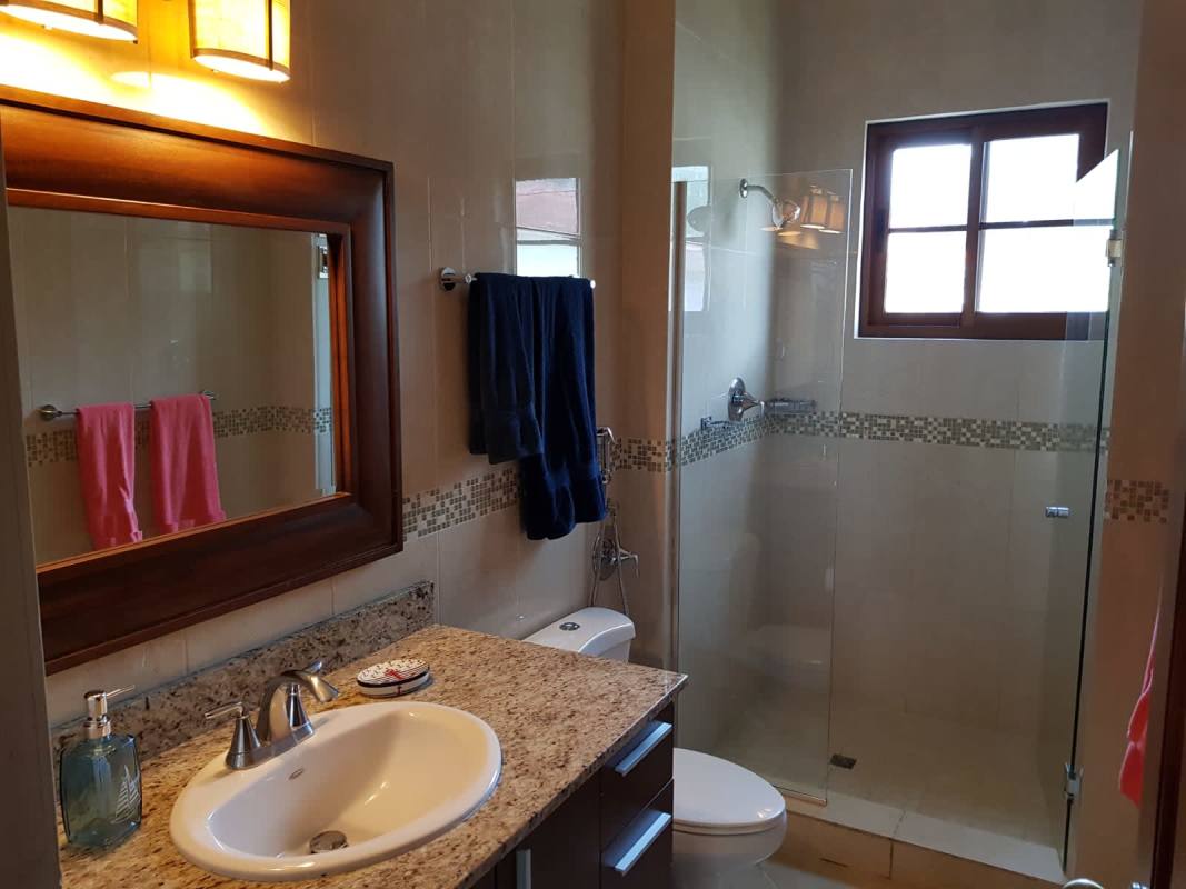 Covered terrace with dining and lounge overlooking lawn Panama home Senderos de Cruces