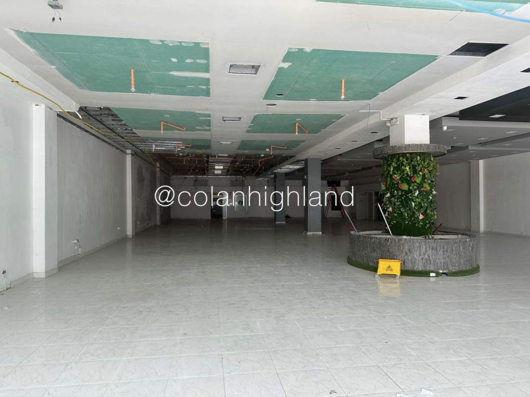 Open storefront interior with unfinished ceiling, tiled floor, central green pillar at Plaza Costa Sur Panama