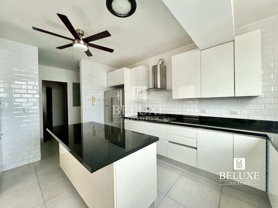 Spacious white kitchen with central island, black countertops, and stainless appliances at PH Jade Tower San Francisco