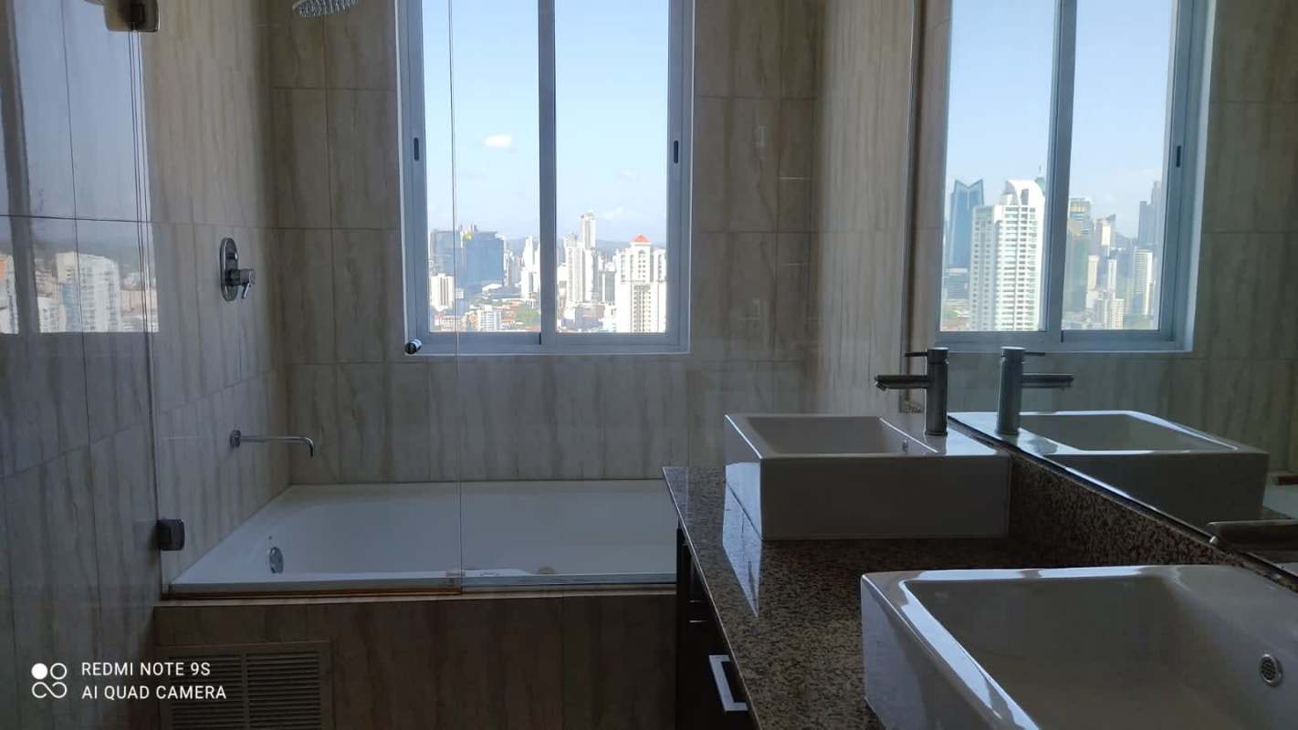 Modern bathroom with double sinks, bathtub, glass enclosure and skyline view in PH Premium Tower San Francisco Panama
