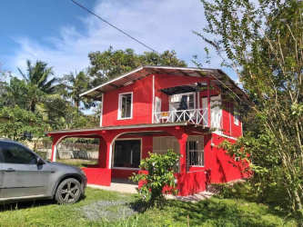 Side of two-story red house with balcony and garden in commercial property Santa Rosa Panama