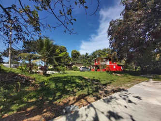 Bright red tropical two-story house with porch balcony greenery Chilibre Panama commercial