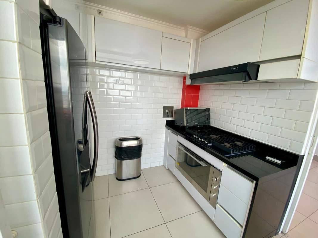 Modern narrow kitchen with subway tile backsplash, white cabinets, stainless appliances in Sky Point Towers