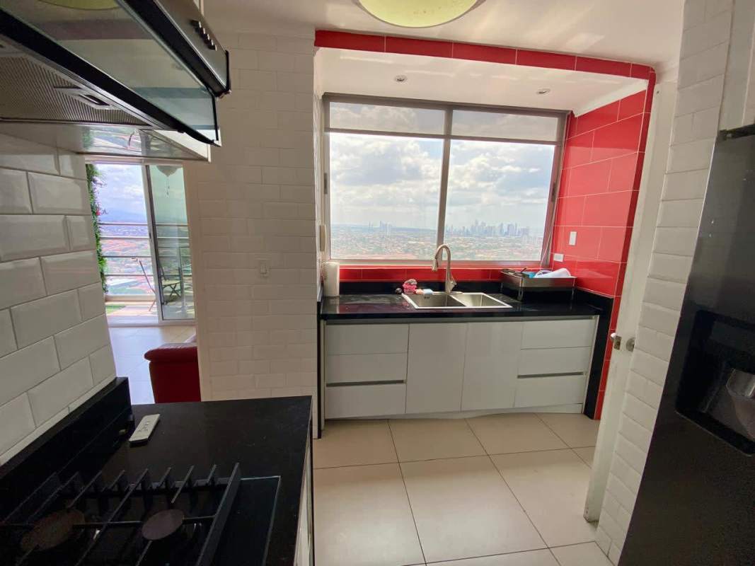 Contemporary kitchen with red accent backsplash and city view window in Sky Point Towers Panama