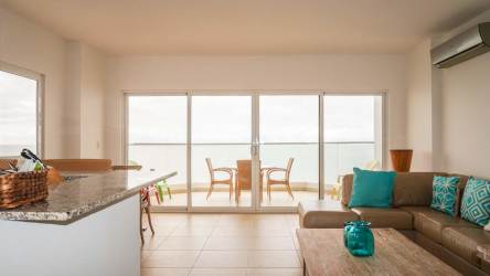 Bright minimalist bedroom with large window, bed, wooden side table, air conditioning at PH Patricia Italia Farallón