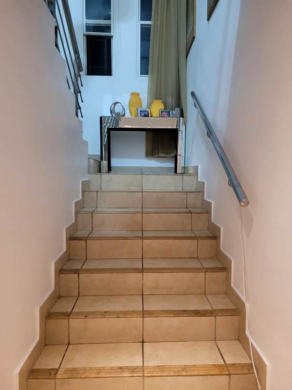 Indoor stairs with ceramic tiles and metal rail in PH Alpes house
