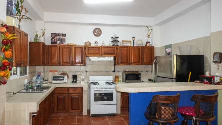 Country kitchen with wooden cabinetry, modern appliances and breakfast bar for sale in Altos del María Panama