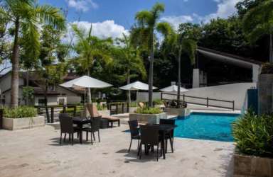 Outdoor pool, palm trees, shaded seating in a residential tropical setting Panama Pacifico