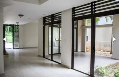 Living room with floor-to-ceiling glass doors opening to patio garden in Nativa Panama Pacifico