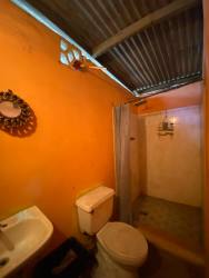 Rustic bathroom with shower curtain, sink, toilet and orange walls in affordable Arraiján rental