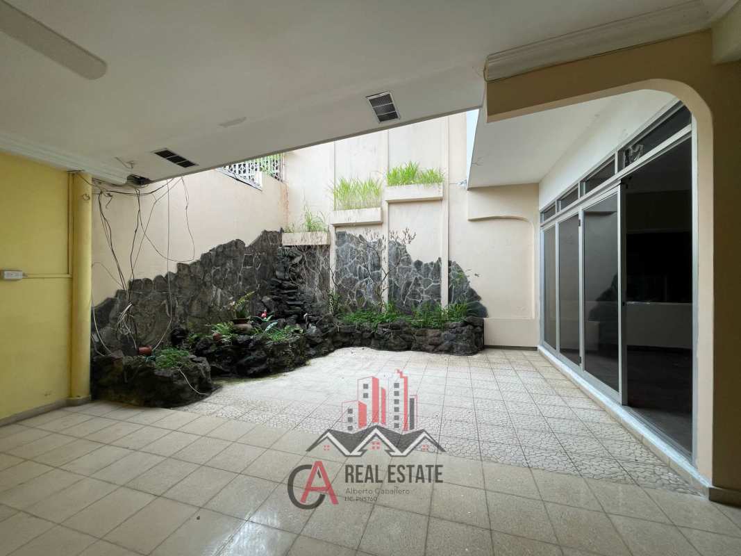 Large indoor courtyard patio with stone planter wall and sliding glass doors in Las Mercedes home
