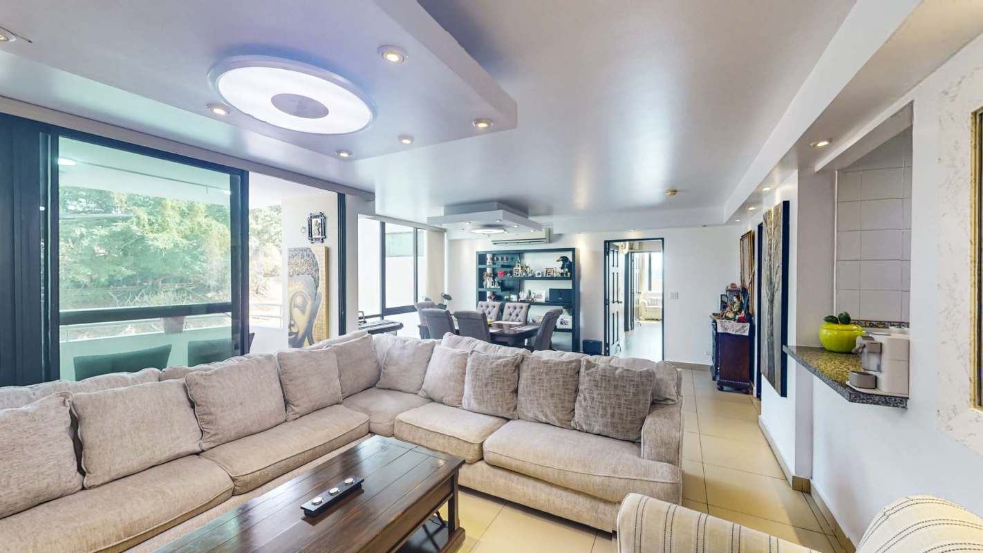 Bright living and dining area with TV mosaic wall, large sofa and dining table at PH Oceanía 100 Plaza Edison Panama