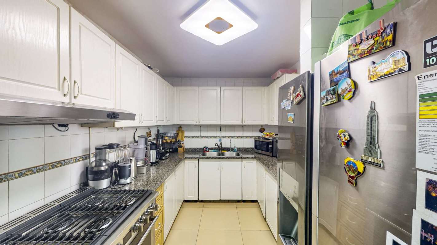 Traditional kitchen featuring granite countertops, white cabinetry, modern appliances in Edison Park Panama City