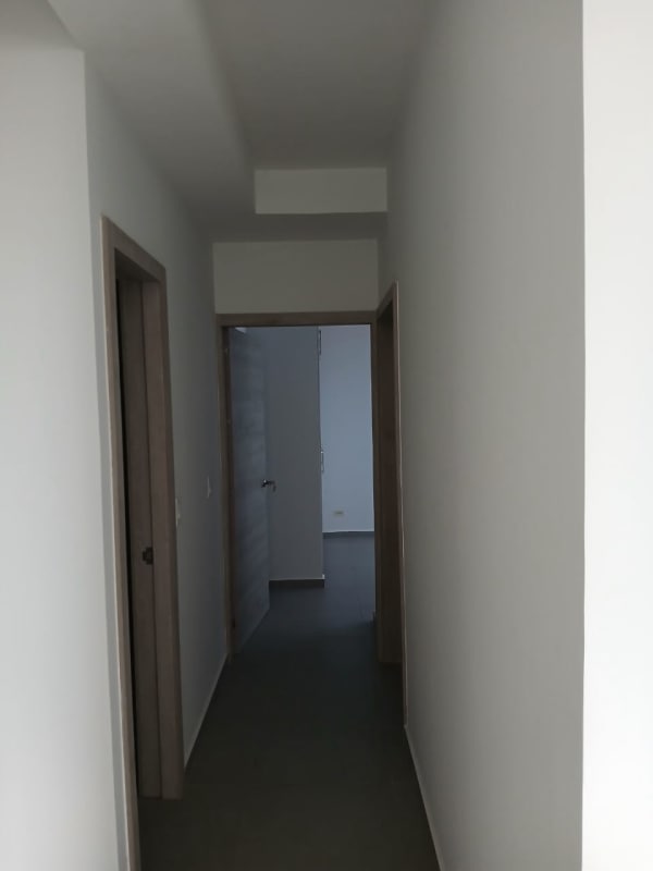Hallway with light gray walls and modern doors inside Signature Point apartment Panama City