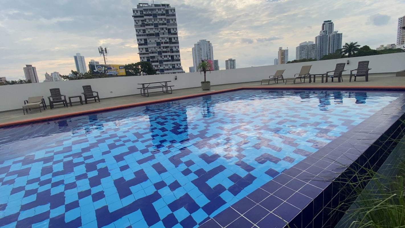 Rooftop swimming pool with blue mosaic tiles, lounge chairs, skyline backdrop at PH Montemar