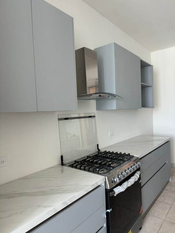 Kitchen with marble countertops, stainless gas stove and vent in Pacific Village Condo Panama