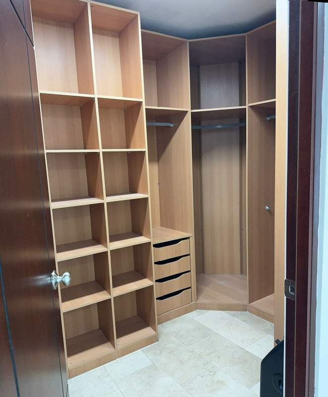 Luxury apartment walk-in closet with built-in wood shelving in Pacific Village Panama
