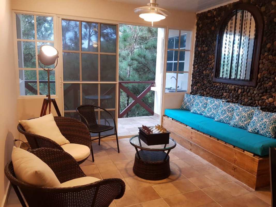 Rustic sunroom with large windows and stone accent overlooking forest in Cerro Azul Panama