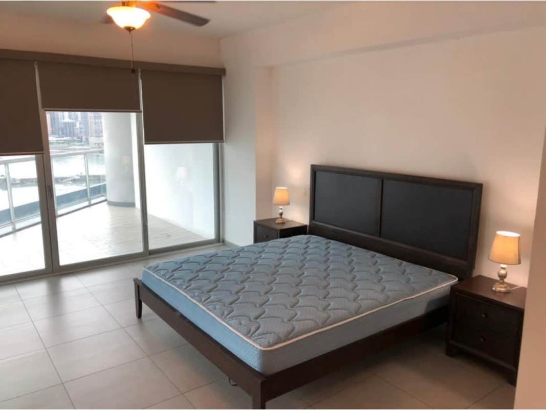 Modern bedroom with sliding glass doors to balcony ocean and skyline views in PH Yacht Club Tower