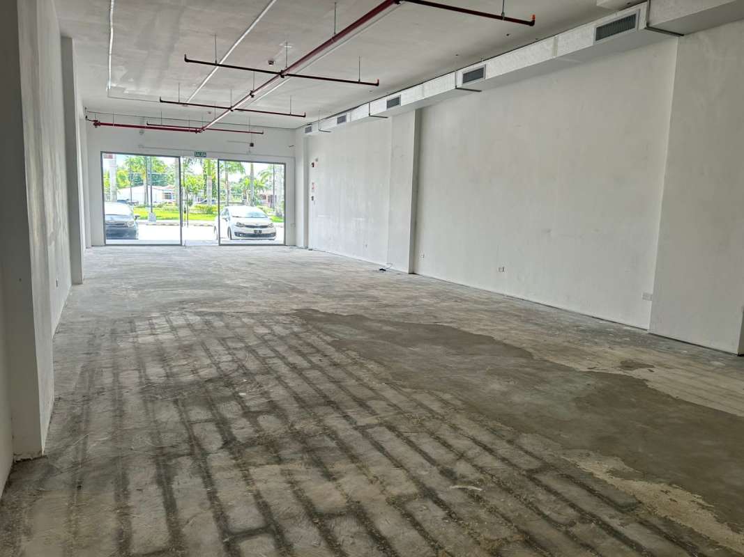 Interior empty unfinished shop unit with glass facade, concrete floor and white walls in Tocumen Panama