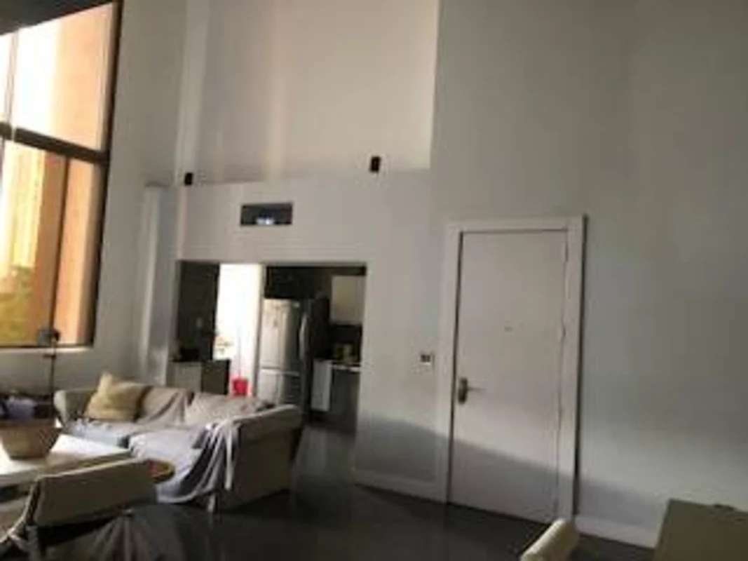 Double-height ceiling living space with large windows, sofa, city views in PH Porta Nova