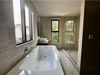 Spacious double-height living room with large windows, tile flooring and stairs in PH Nativa house