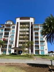 Exterior of contemporary multi-story beachfront condo with balconies, palm trees and landscaped entrance Playa Escondida Panama
