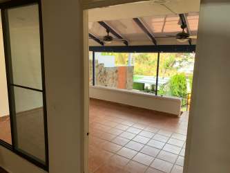 Bright enclosed sunroom with terracotta tiled floor, windows and outdoor views in Coronado Panama