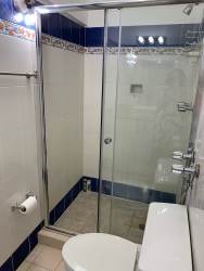 Bright bathroom with blue trim, glass shower enclosure, modern fixtures at Coronado duplex home