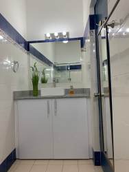 Contemporary bathroom with large mirror, glass shower, white vanity in Coronado Panama duplex