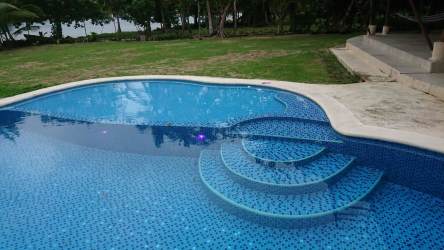 Outdoor pool with curved design, mosaic tiles surrounded by garden Panama