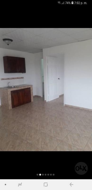 Small kitchen with brown cabinets and adjacent bathroom, tiled interior space San Miguelito