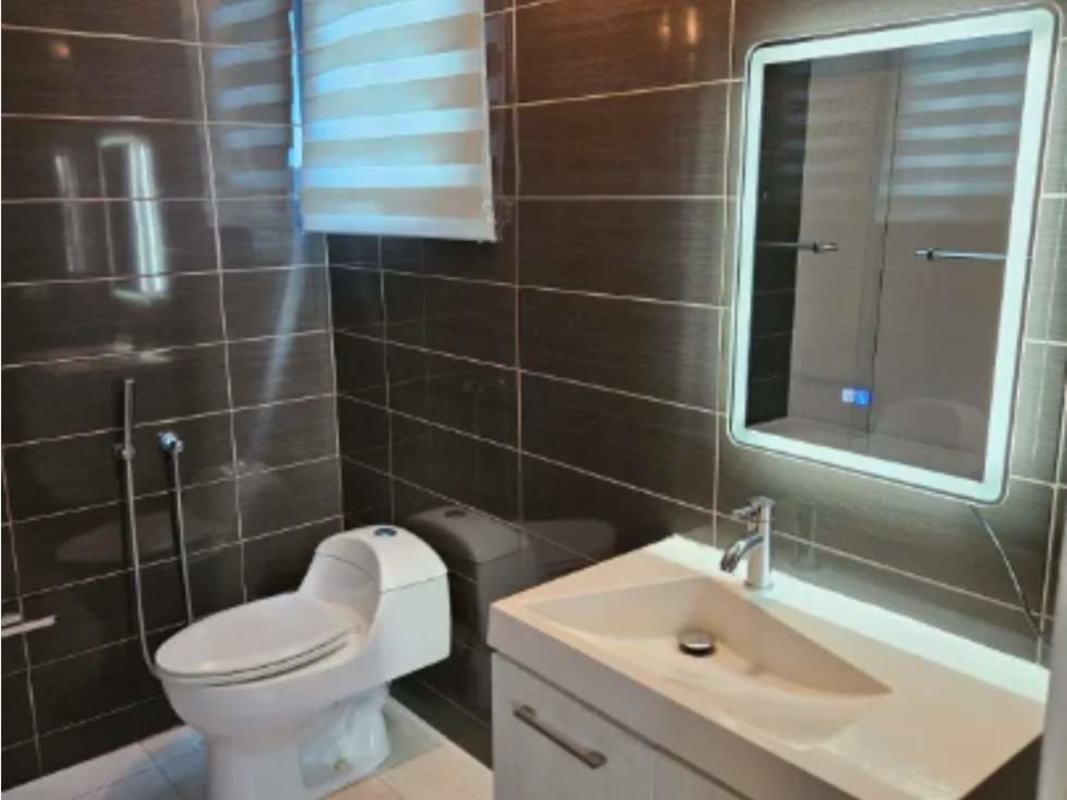 Bathroom with illuminated mirror, dark tiles, white fixtures PH Miro El Cangrejo Panama