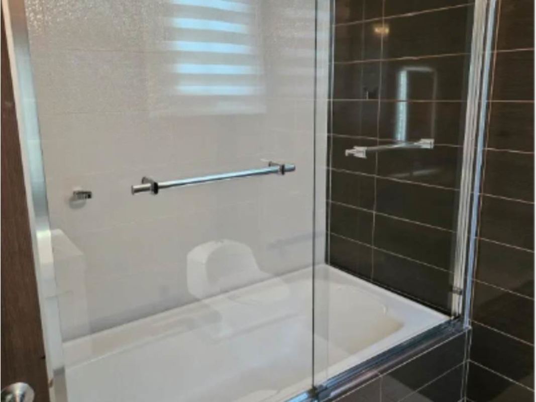 Modern bathroom with bathtub, glass enclosure, dark and white tile at PH Miro Panama