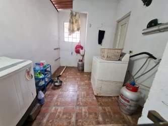 Laundry area with washing machine, freezer, gas cylinders, and side door in house Arraiján