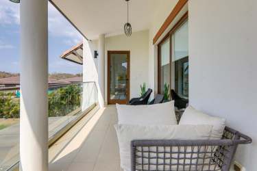 Covered balcony seating area on second floor with glass railing and panoramic Pacific Ocean views Casamar Panama