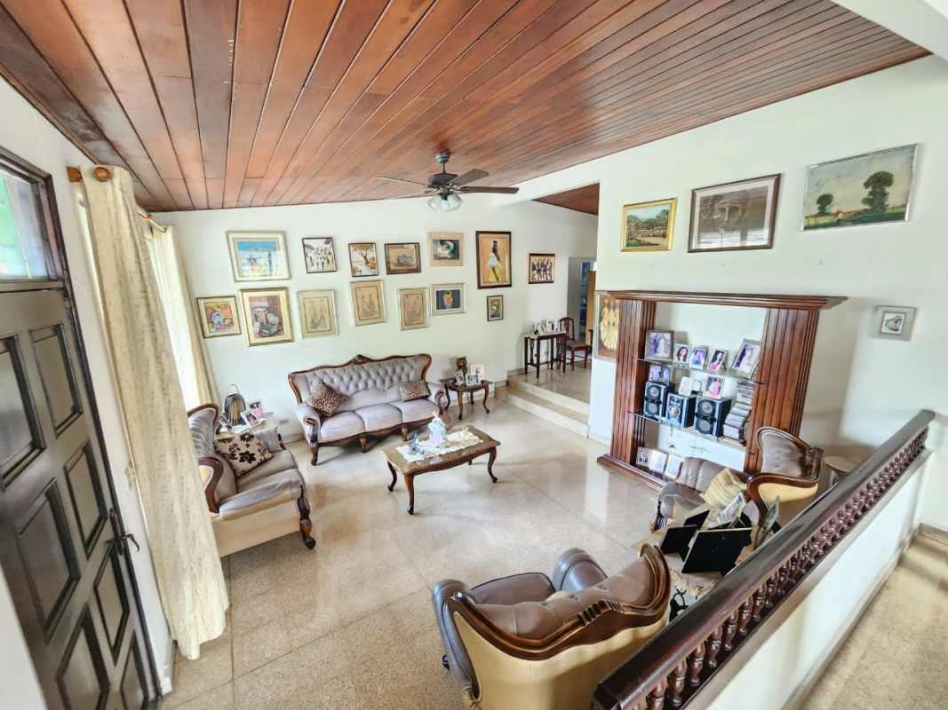Traditional living room with wood ceiling, classic furniture, art wall in family home Betania Panama