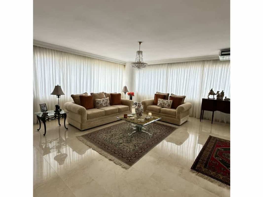 Traditional dining room with chandelier and curtains overlooking Panama City skyline in PH Elite La Cresta