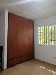Bedroom with large wooden wardrobe, window, tiled floors in house Mirador del Bosque Guararé Panama