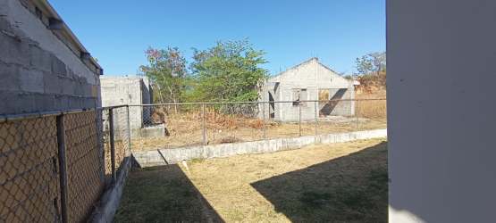 Backyard space with fencing, unfinished structures, dry patches, and trees on land for sale Chitré Panama